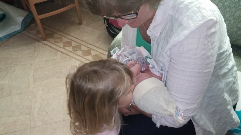 Big sister Eden giving baby Faith smooches. Mia is holding her new granddaughter. 